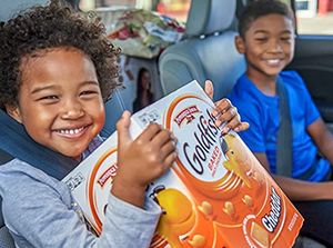 A child in a car holding a box of Goldfish crackers