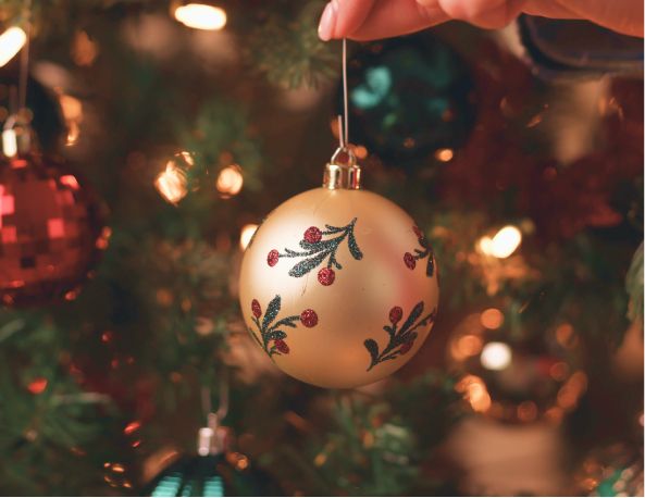 An ornament with mistletoe hanging from a christmas tree