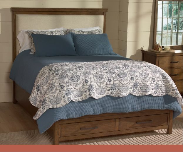 A bed with teal blue covers and a floral comforter set.
