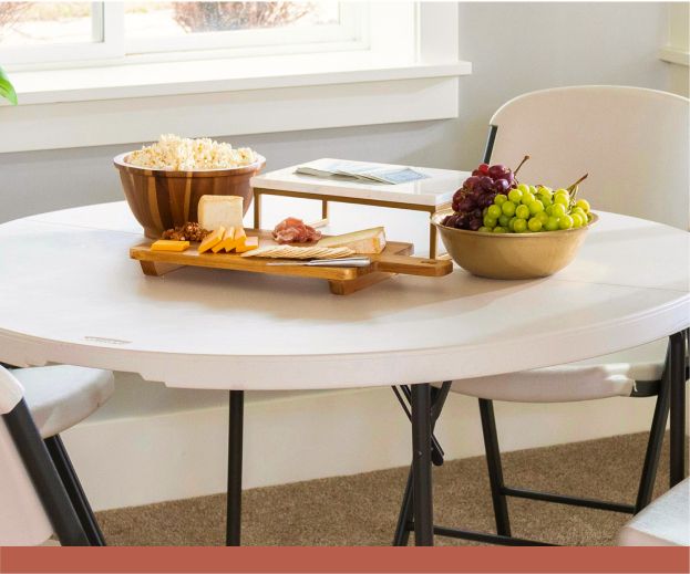 A white folding table with a charcuterie spread on top of it.