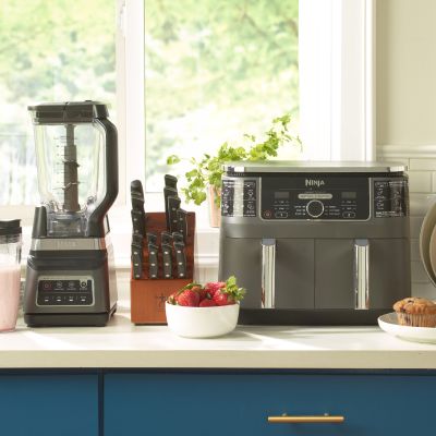 Image: Kitchen counter with blender, knife block, toaster oven, and fruit bowls.