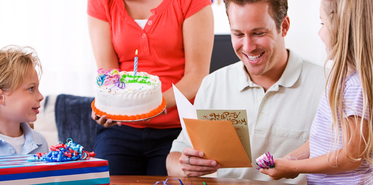 A dad reading a birthday card from his wife and 2 kids
