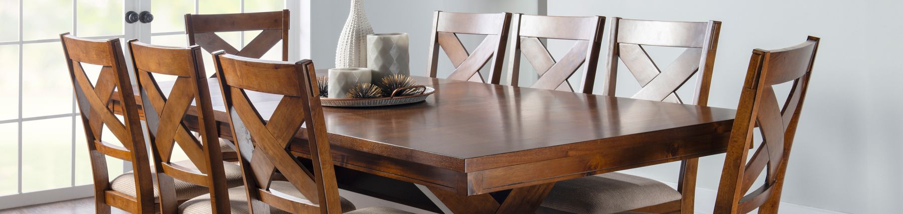 A rich colored, wooden dining table with a centerpiece and 8 matching chairs 