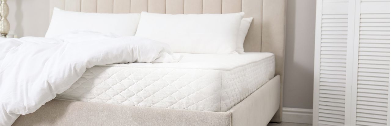 A picture of a mattress with pillows and a comforter.