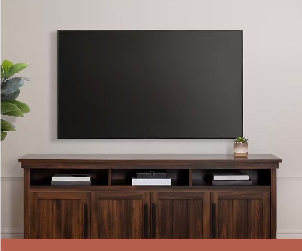 A tv mounted above a dark wood media center