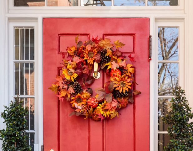 A fall wreath on a red front door.